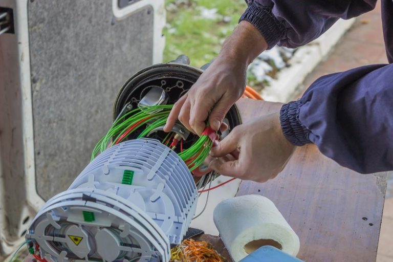 Fibre optic technician rolls of fibre-optic cables inside a splice organiser tray.