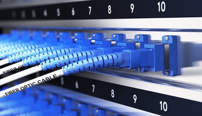 Close up of optical fiber optic telecommunication equipment and patchcords inside a network infrastructure. Blur effect with focus on one cable, blue tones.